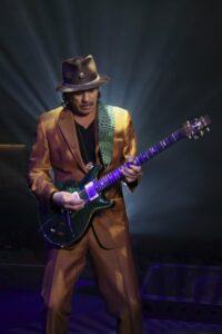 Carlos Santana playing a purple guitar.