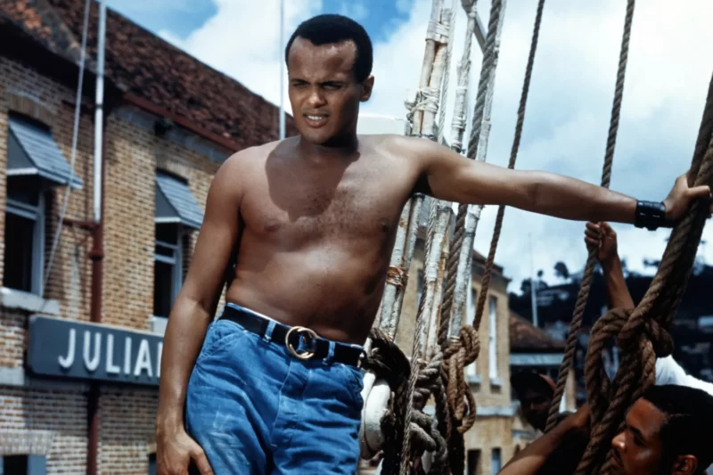 Color photo of Harry Belafonte shirtless on set of Island in the Sun